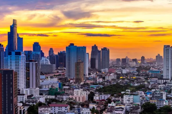 Skyline von Bangkok bei Sonnenuntergang mit hohen Gebäuden und einem lebhaften orangefarbenen Himmel