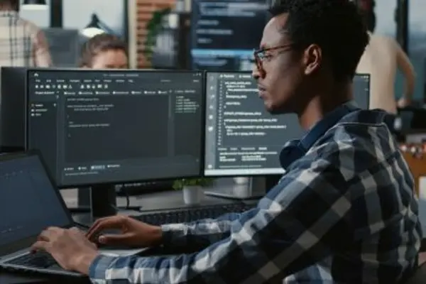 Workspace with multiple monitors displaying programming code.