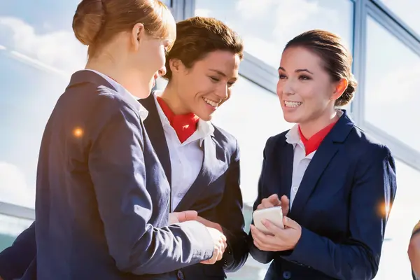 Drei Crew-Mitglieder in Uniform im Gespräch mit Smartphone