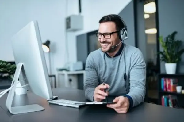 Man with headphone sitting in front of computer screen on desk