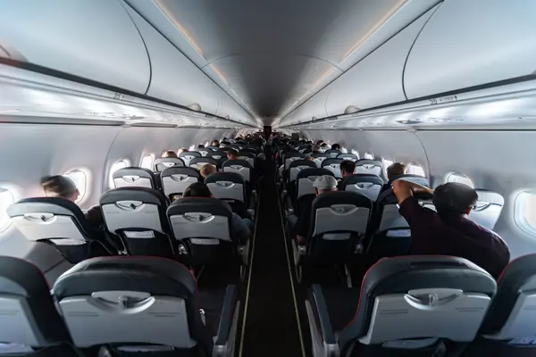 View through an airplane cabin with occupied rows of seats