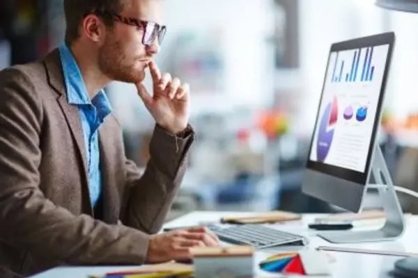 Person working on computer with charts and data analysis in office