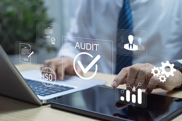 Business professional working on a laptop with digital audit and ISO icons
