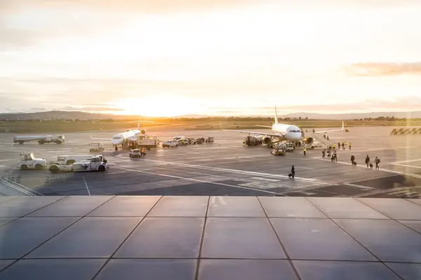 Airport tarmac with aircraft and ground handling at sunrise