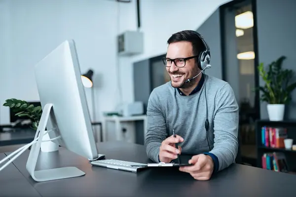 Support employee with headset working at a computer in a modern office