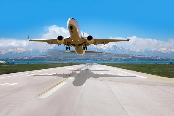Commercial aircraft taking off from a runway with mountainous terrain in the background
