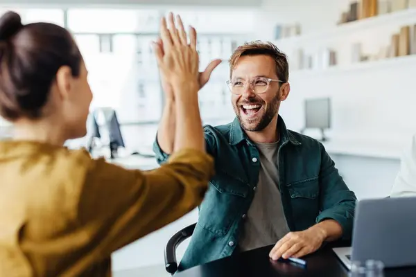 people and or colleagues are together in the office and giving each other a high five