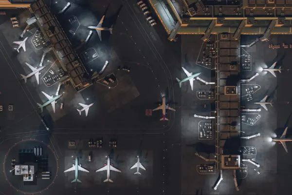 Aerial View of a 3D Commercial Airport Render with Airplanes, Passenger Terminals, Runway and Service Machinery. Top Down View of Modern VFX Aircrafts Moving International Port at Night time.