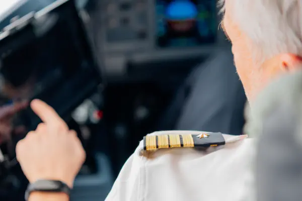 Senior male pilot using digital touchscreen in airplane cockpit