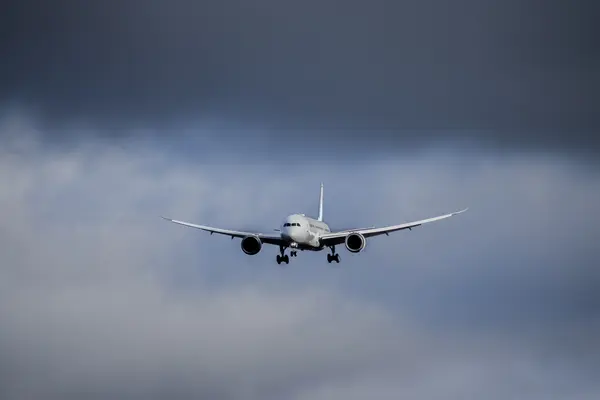 Commercial aircraft approaching through a cloudy sky with landing gear deployed