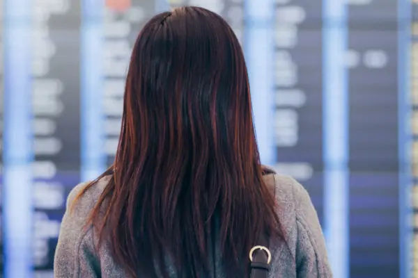 Person facing an airport departure board checking flight information and schedules