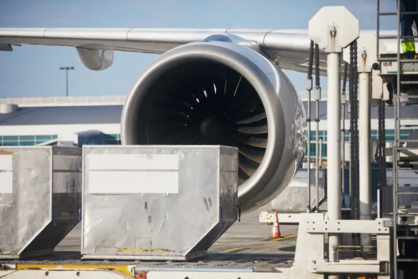 Aircraft engine at the gate with cargo containers and ground handling equipment