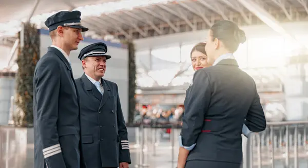 Flughafenpersonal in Uniform steht zusammen und unterhält sich in einem modernen Terminal