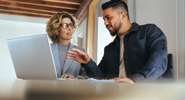 Zwei Personen arbeiten gemeinsam an einem Laptop in einem modernen Büro