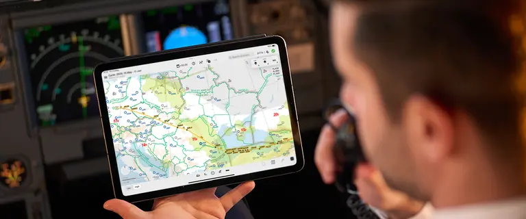 Pilot holding a device which is showing navigation solution Lido mPilot