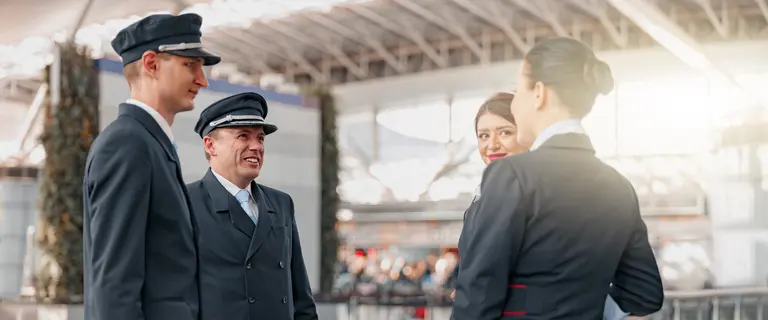 Flughafenpersonal in Uniform steht zusammen und unterhält sich in einem modernen Terminal