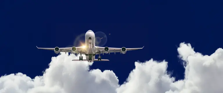 Passagierflugzeug fliegt durch Wolken vor blauem Himmel