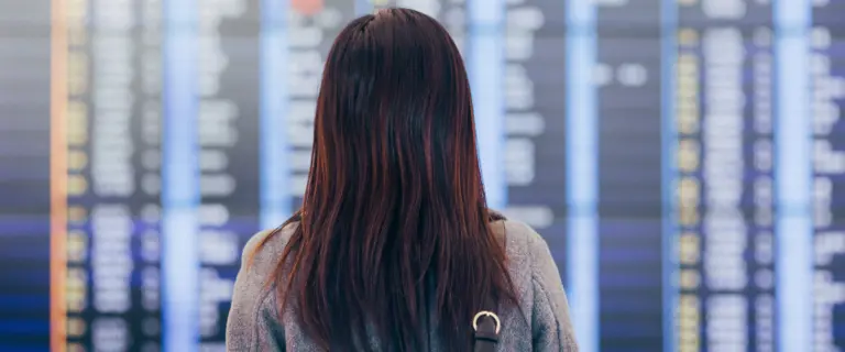 Person facing an airport departure board checking flight information and schedules
