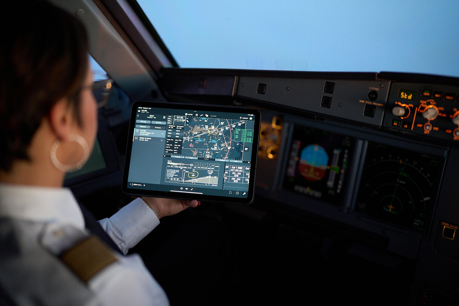 Pilotin im Cockpit während des Flugs und schauend auf einen Bildschirm