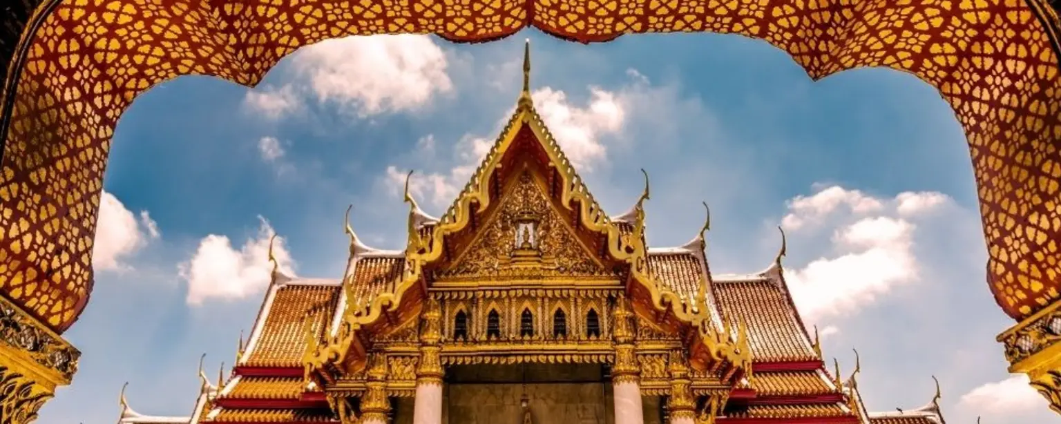 Ornate temple in Bangkok with a decorative entrance and intricate archway in the foreground