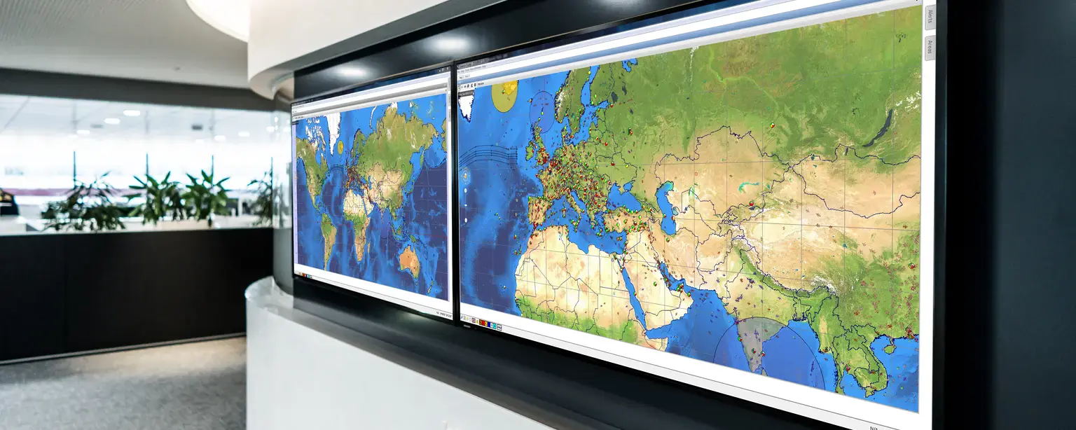 Großbildschirme in einem Integrated Operations Control Center mit globalen Karten zur Überwachung und Steuerung des Flugbetriebs